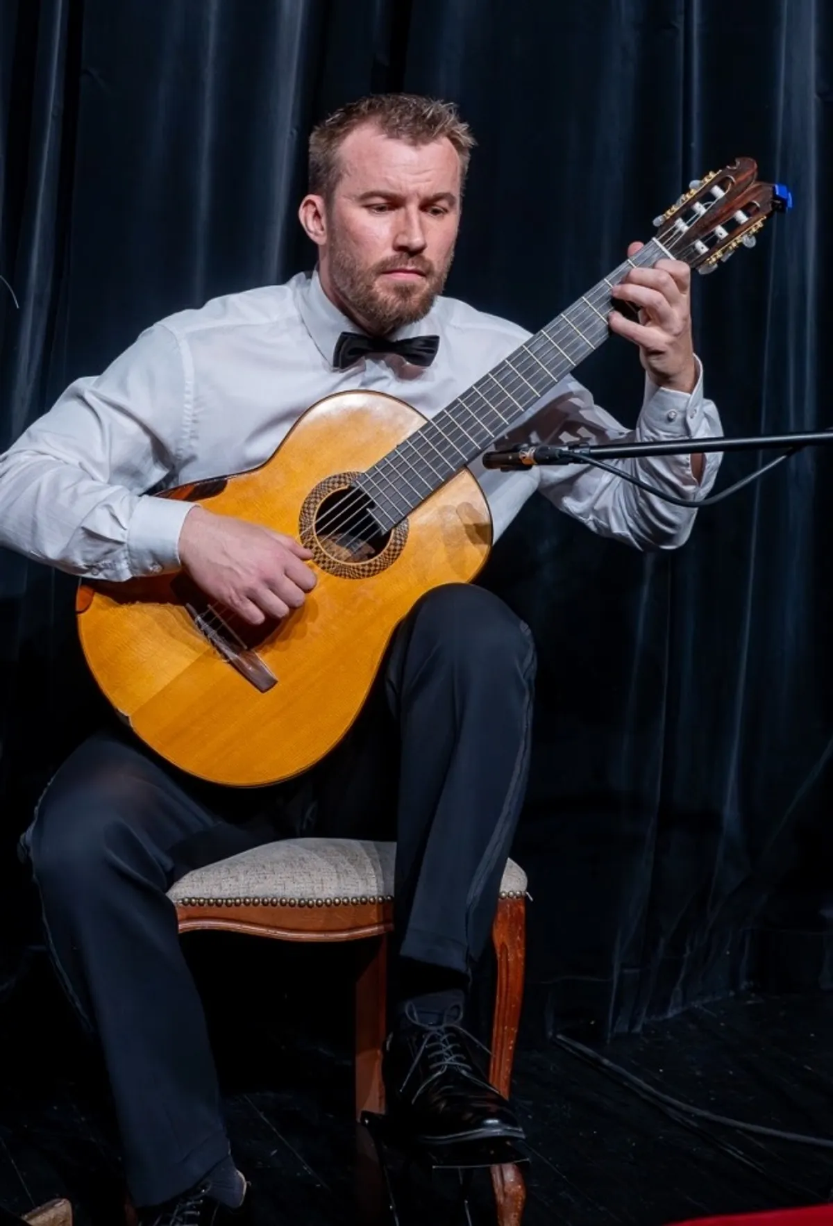 Tomasz Modranka na scenie z gitarą klasyczną